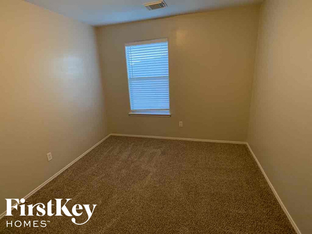 A room with a carpeted floor and a window with blinds.