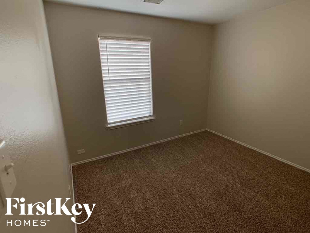 A room with a carpeted floor and a window with blinds.