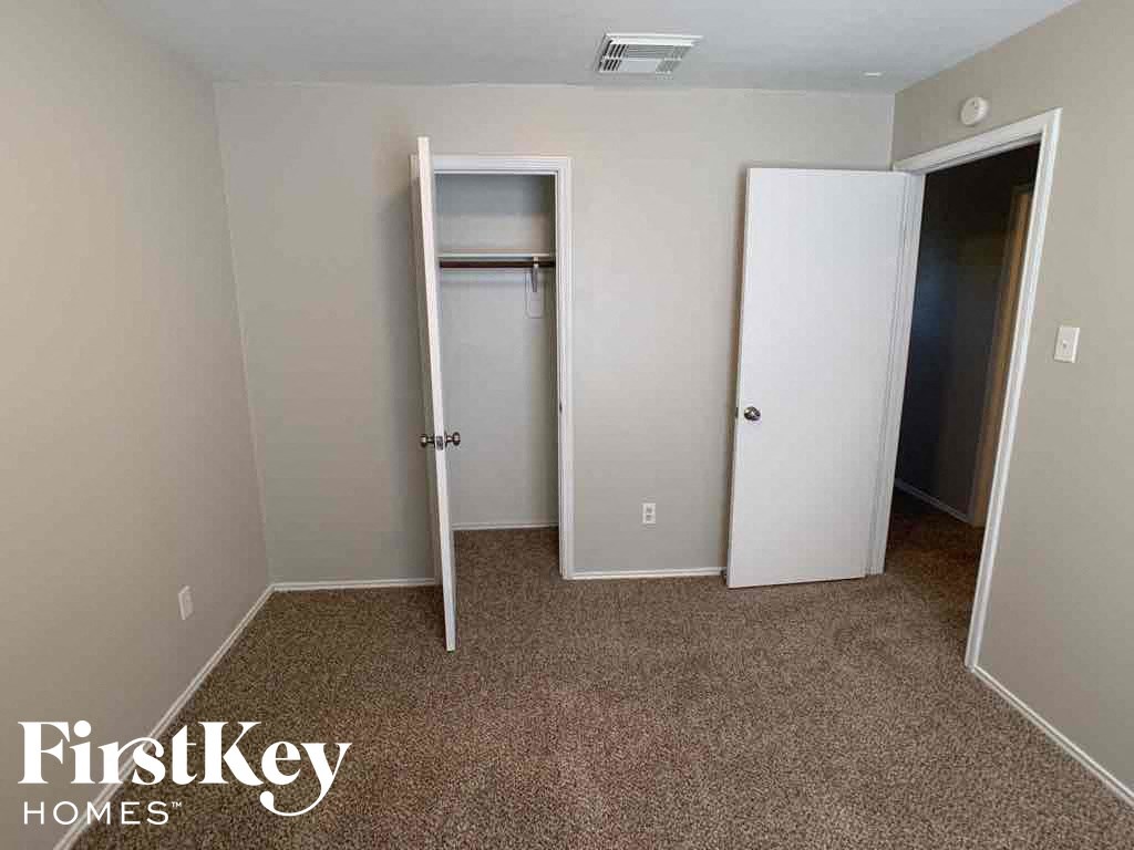 A room with a carpeted floor and two doors, one of which is open.