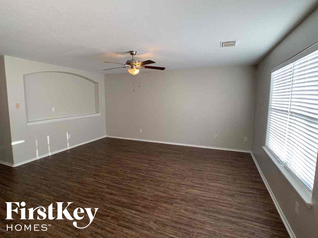 A room with a ceiling fan and wooden flooring.