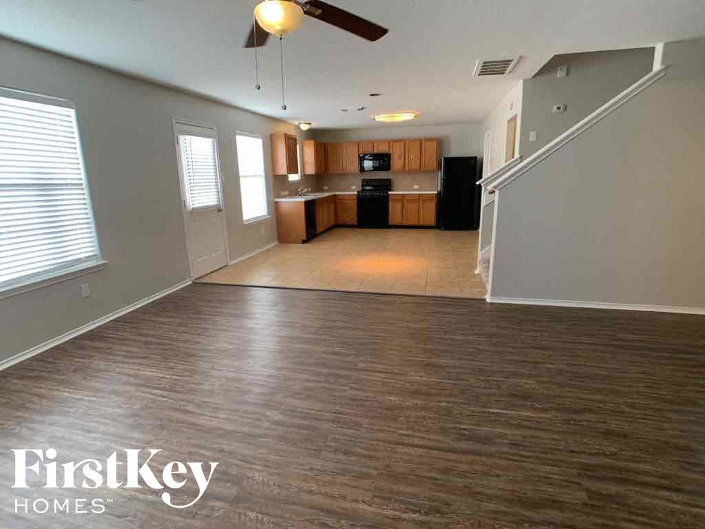 A spacious living room with wood flooring and a ceiling fan.