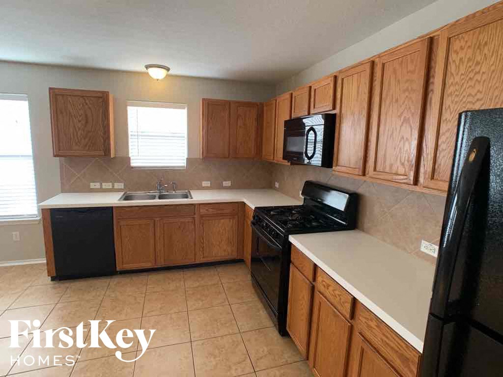 A kitchen with wooden cabinets and black appliances.