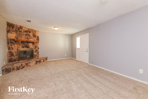 A living room with a fireplace and carpeting.