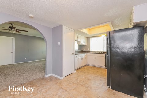 A kitchen area with a black fridge and a fan on the ceiling.