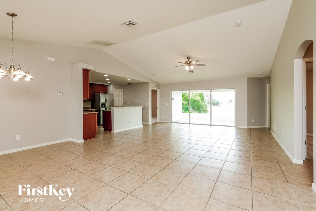 A spacious living room with a ceiling fan and tiled flooring.