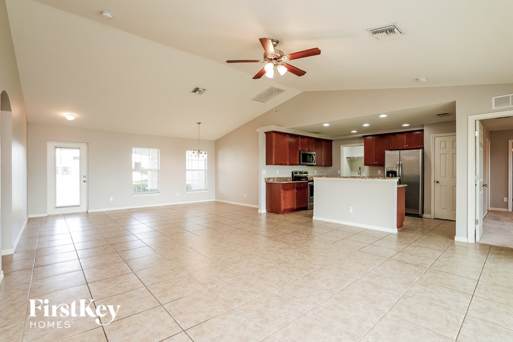 A spacious living room with a kitchen in the background.