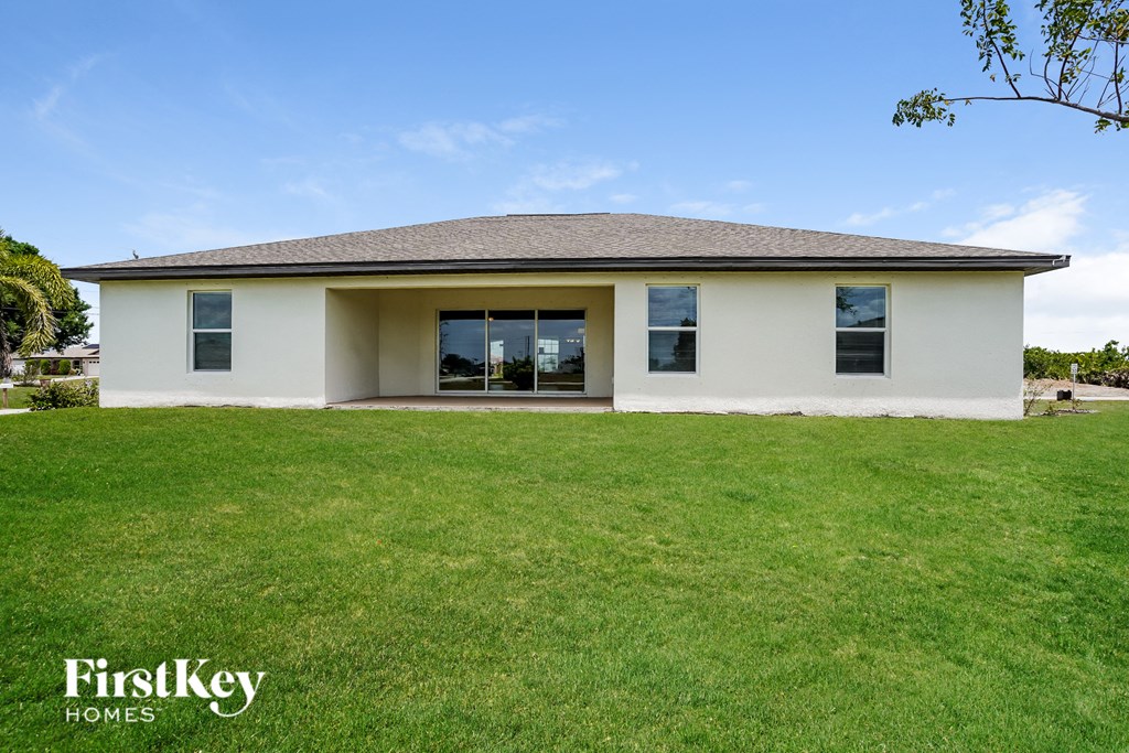 A white house with a brown roof and a grassy lawn in front.