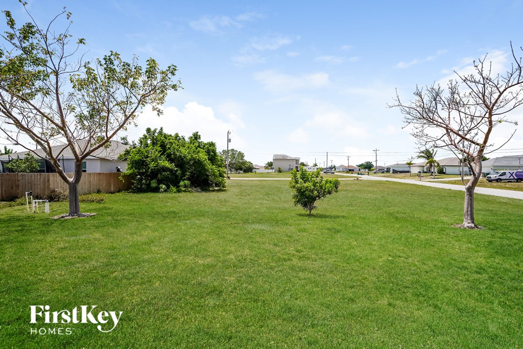 A grassy field with trees and a sign that says "FirstKey Homes".