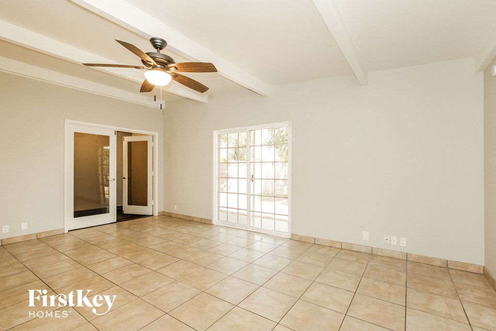 an empty living room with a ceiling fan and tiled floor