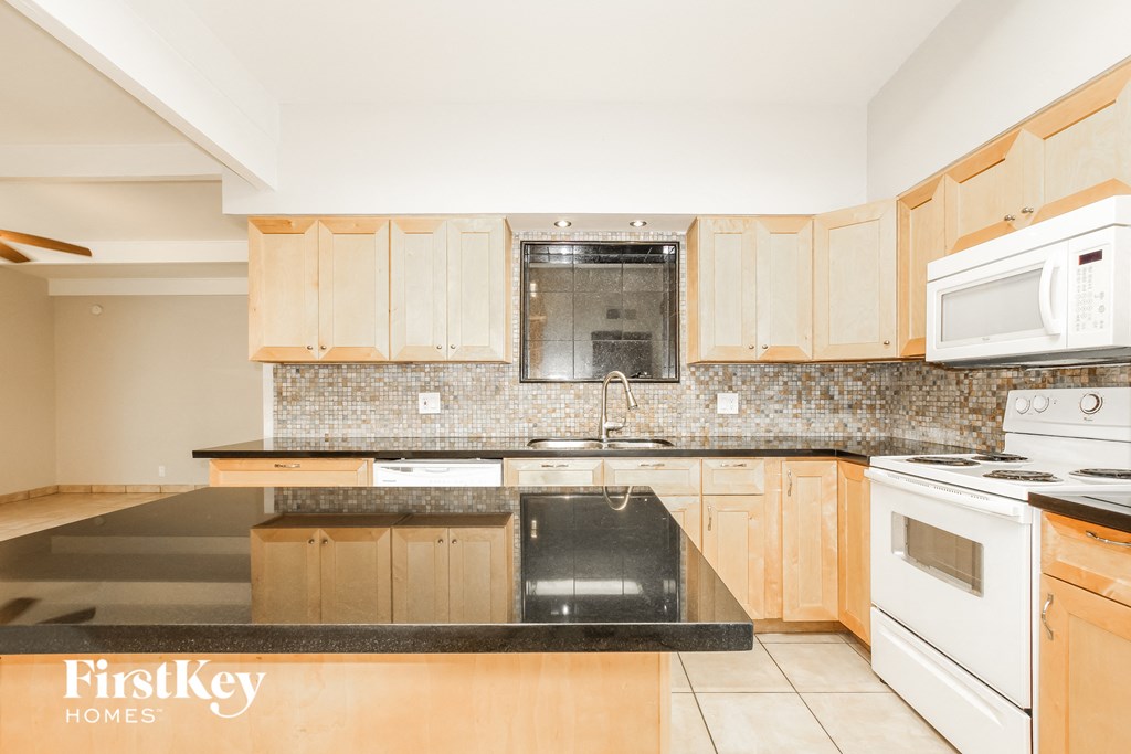 a kitchen with wooden cabinets and black counter tops and white appliances