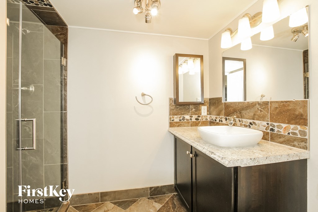 a bathroom with a sink and a shower and a mirror
