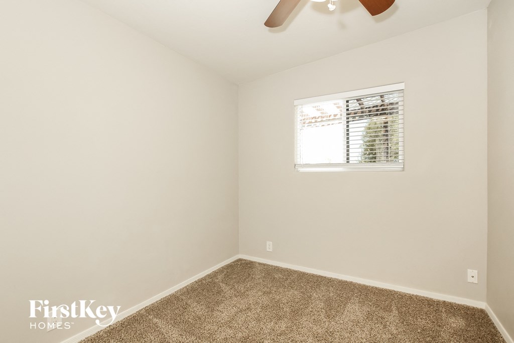a room with carpet and a window and a ceiling fan