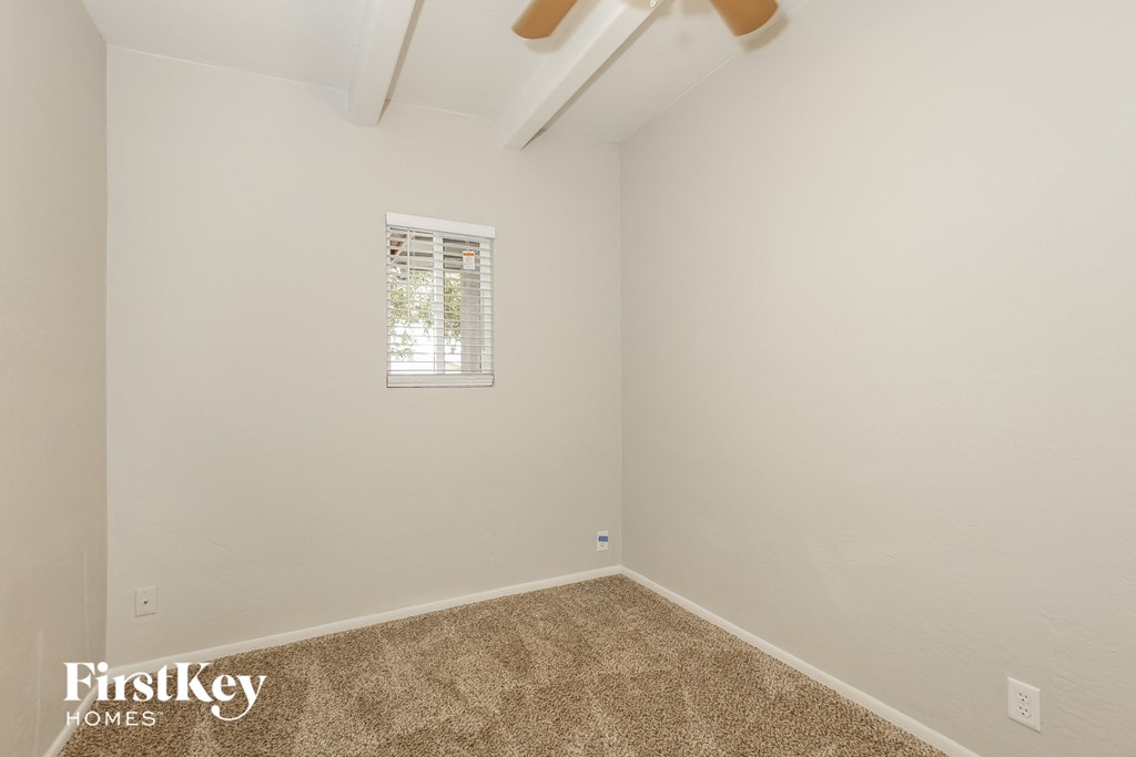 a bedroom with white walls and carpet and a window