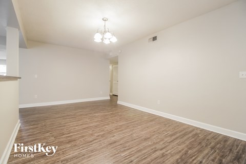 a spacious living room with wood flooring and white walls