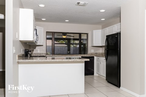A kitchen with a black fridge and white cabinets.