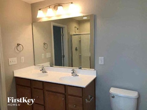 A bathroom with a white countertop and a mirror above it.