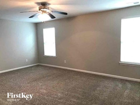 A room with a ceiling fan and two windows.