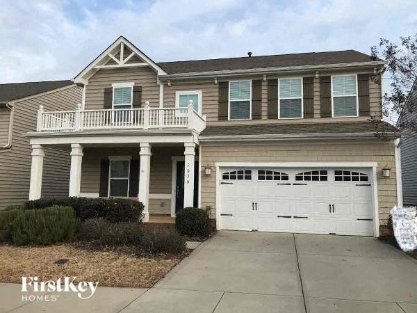 A two-story house with a garage and a balcony.