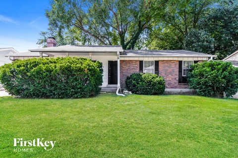 A house with a lawn and trees in the background.