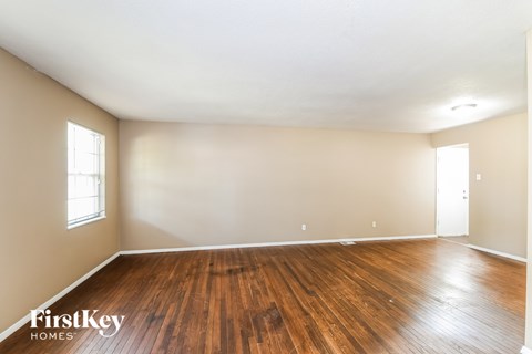 A room with wooden floors and two windows.