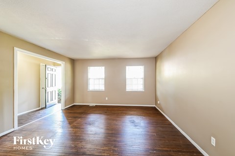 A room with wooden floors and two windows.