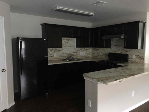 A kitchen with black cabinets and a marble countertop.