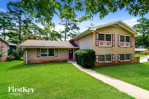 A house with a red door and a green lawn in front.