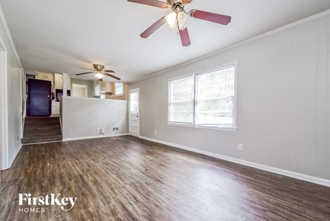 A room with a ceiling fan and wooden flooring.
