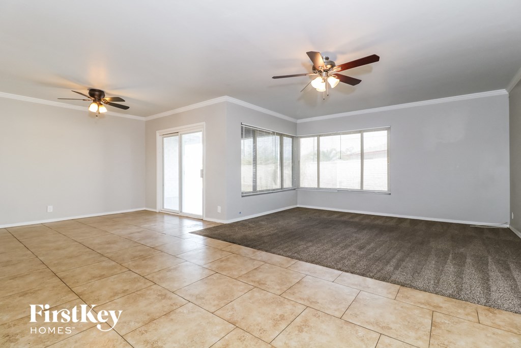 the living room of an empty house with two ceiling fans