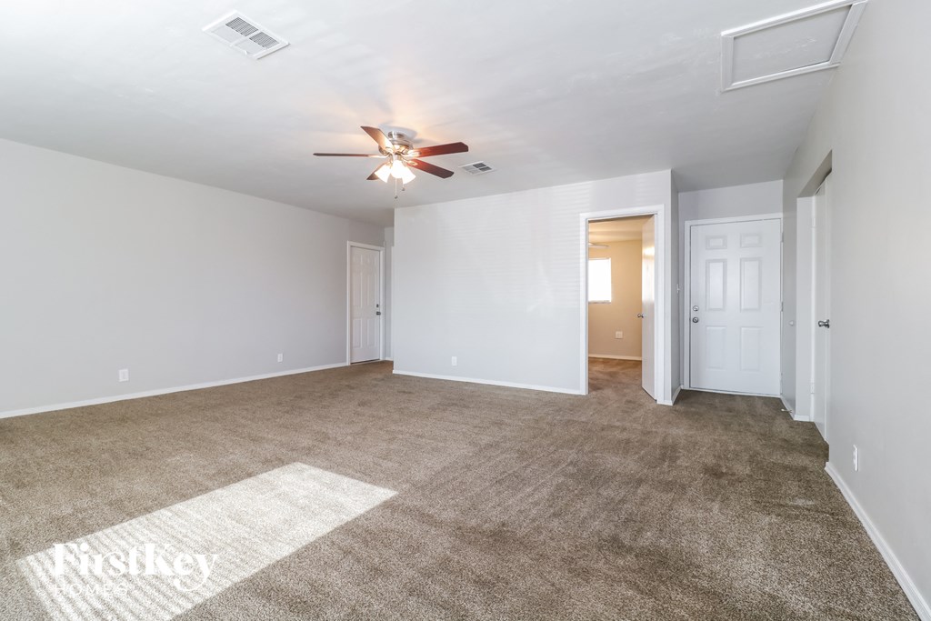 an empty living room with carpet and a ceiling fan