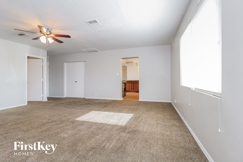 an empty living room with a ceiling fan and white walls
