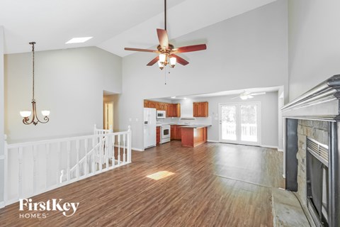 A spacious living room with a fireplace and a ceiling fan.