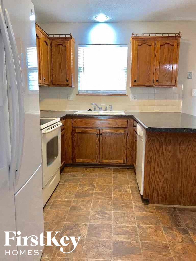 an empty kitchen with wooden cabinets and white appliances