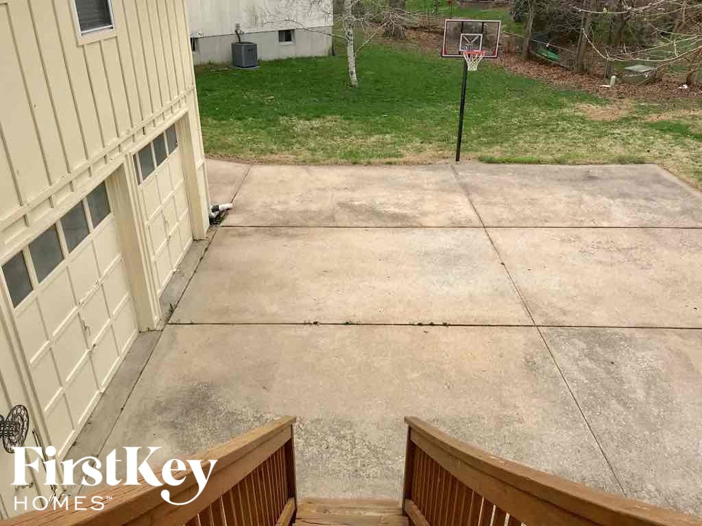 a driveway with a basketball hoop on the side of a house