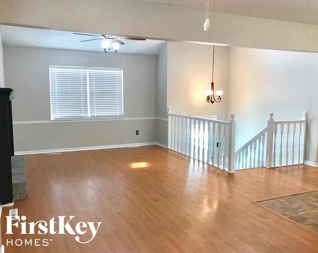 an empty living room with a staircase and wood flooring