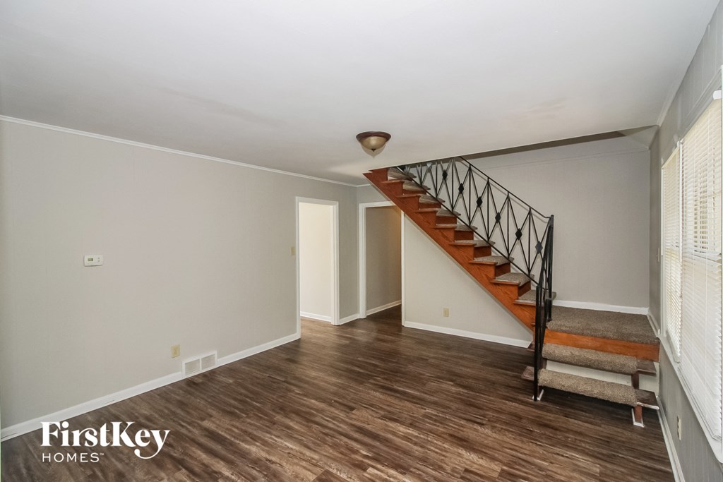 a renovated living room with a staircase and wood flooring