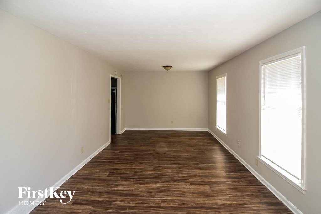 an empty living room with wood floors and white walls