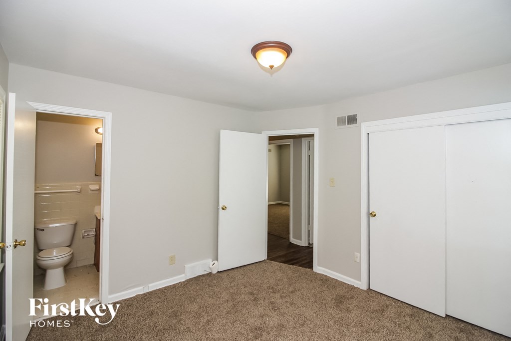 a bedroom with a door to the bathroom and a toilet and a closet