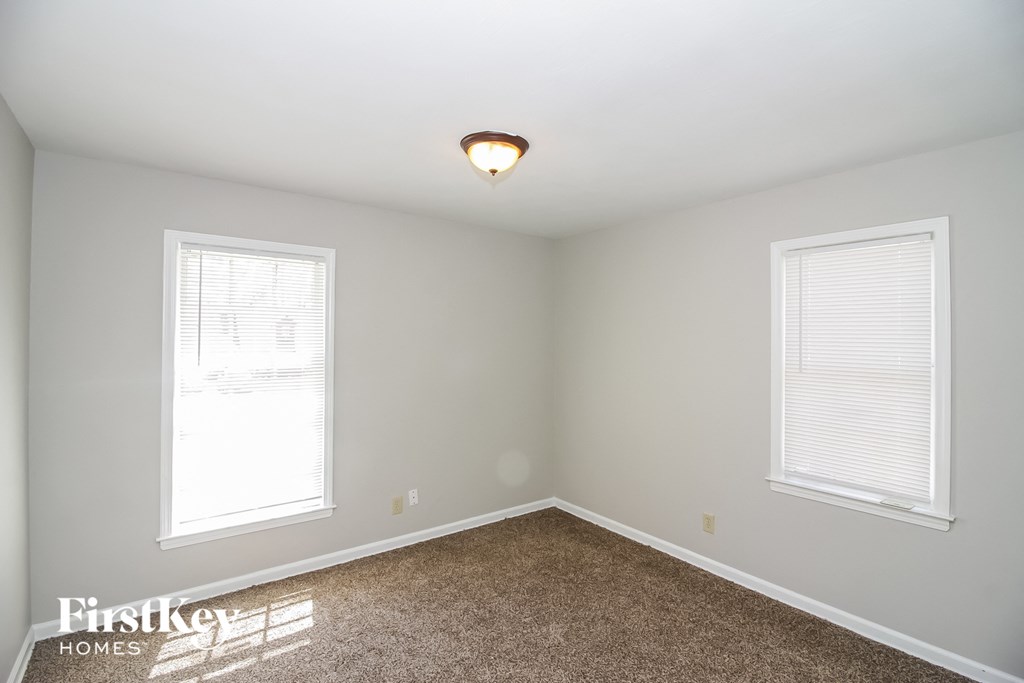a bedroom with two windows and a carpet