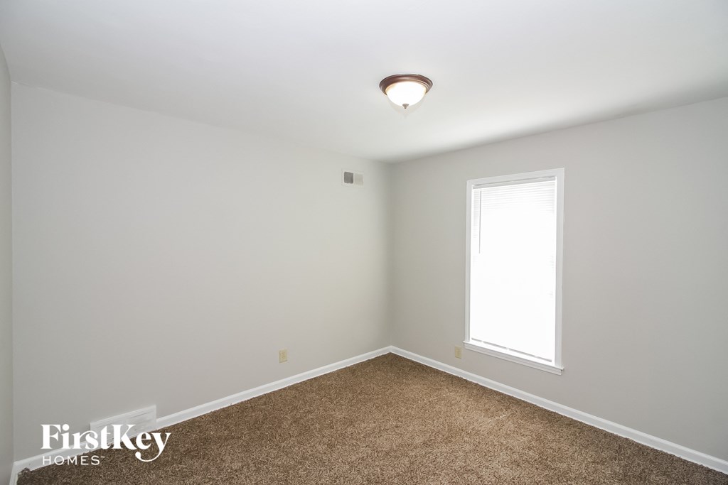 a bedroom with white walls and a window and carpet