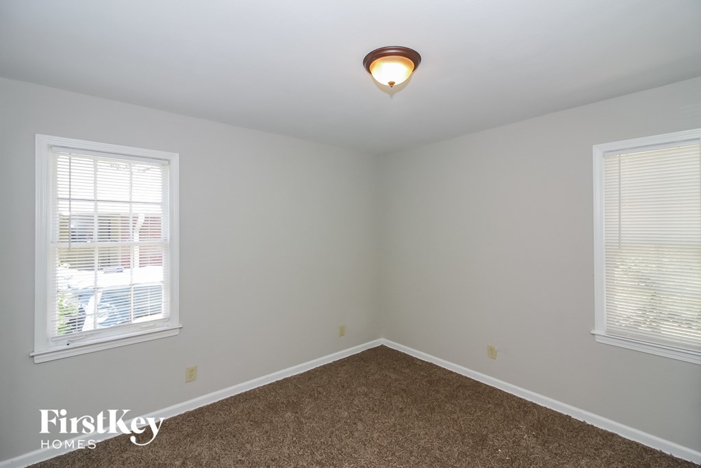 a bedroom with a carpeted floor and two windows