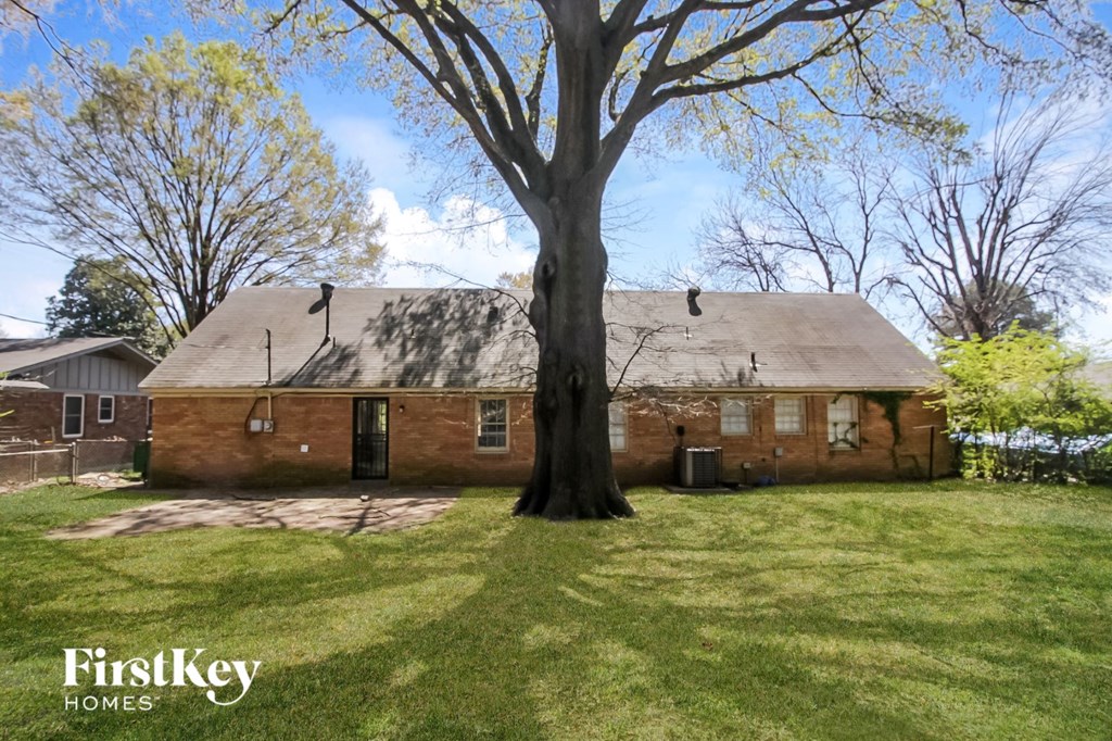 a red brick house with a large tree in the yard