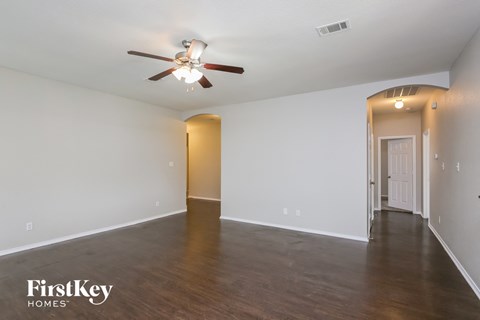 an empty living room with white walls and a ceiling fan