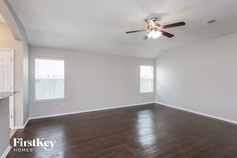 an empty living room with wood floors and a ceiling fan