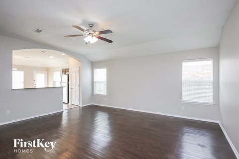 an empty living room with wood floors and a ceiling fan