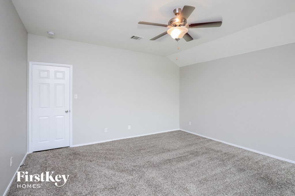 the spacious living room with ceiling fan and carpet