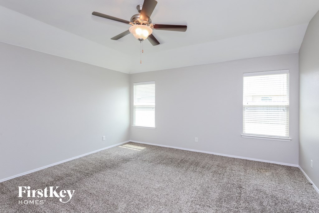 a living room with a ceiling fan and a carpet