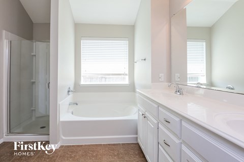 a white bathroom with a tub and a sink and a shower