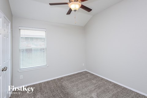 a bedroom with a ceiling fan and a carpet