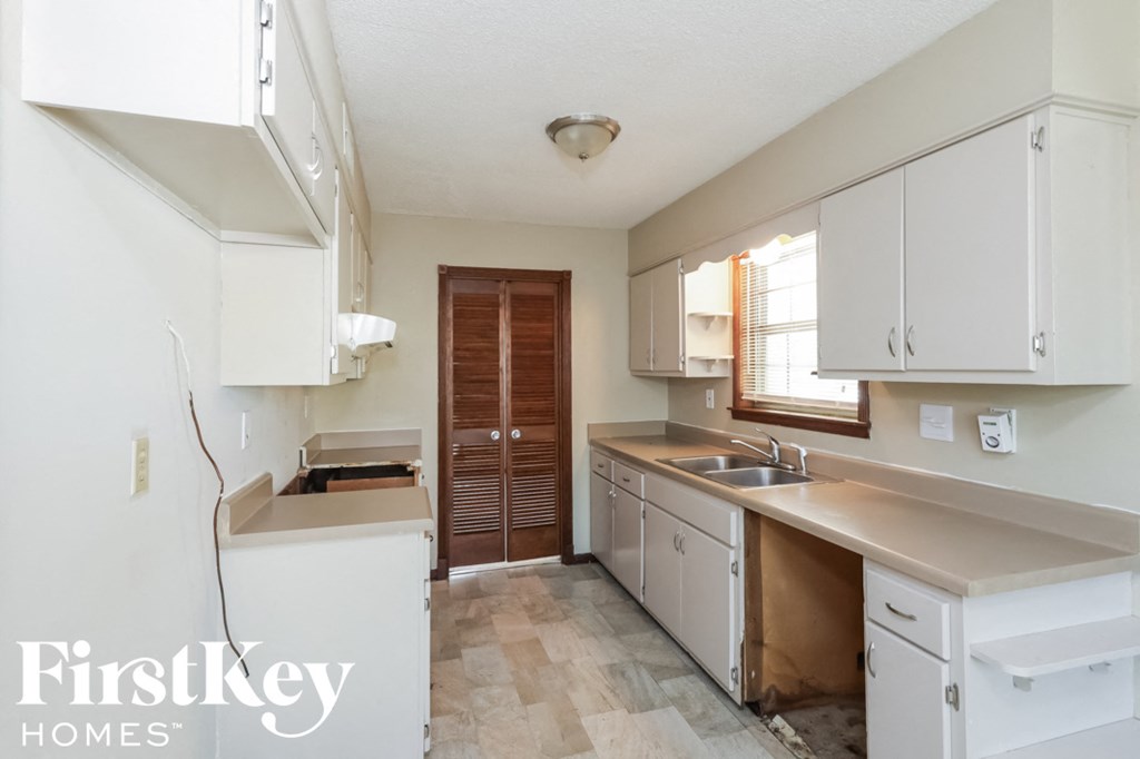 A kitchen with white cabinets and a wooden door.